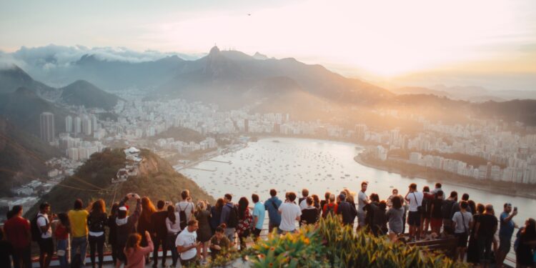 group of people standing facing lake view