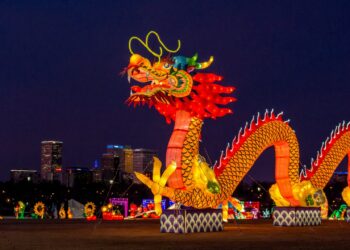 people walking on street with dragon statue during night time